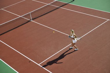 genç kadın oyun Tenis açık portakal Tenis alanında erken sabah saat yerleştirmek.