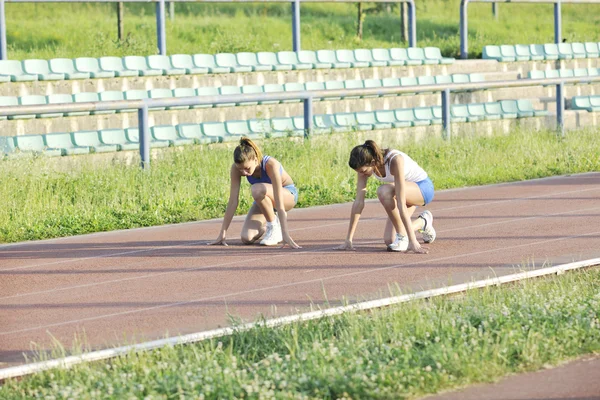 Duas meninas correndo na pista de corrida atlética — Fotografia de Stock