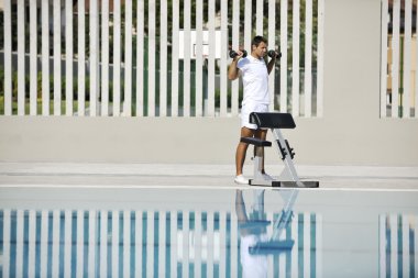 Genç sağlıklı sporcu havuz başında egzersiz yapıyor.