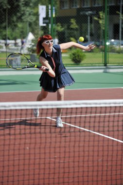 genç kadın oyun Tenis açık portakal Tenis alanında erken sabah saat yerleştirmek.