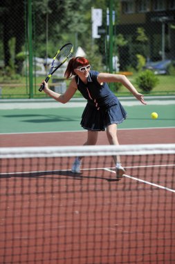 genç kadın oyun Tenis açık portakal Tenis alanında erken sabah saat yerleştirmek.