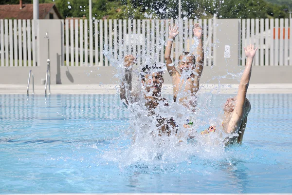 Счастливая молодая семья веселится в бассейне — стоковое фото