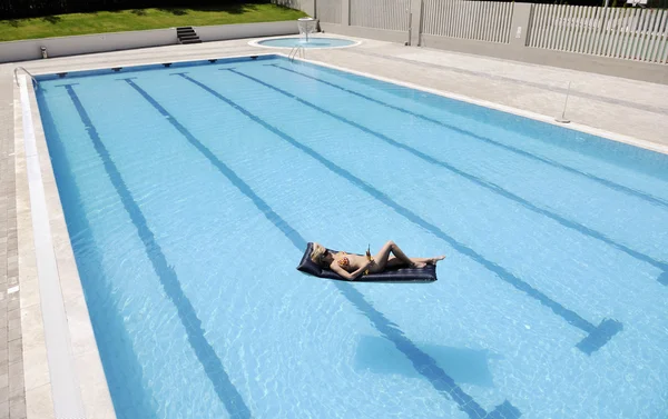 Güzel bir kadın yüzme havuzunda rahatlar. — Stok fotoğraf
