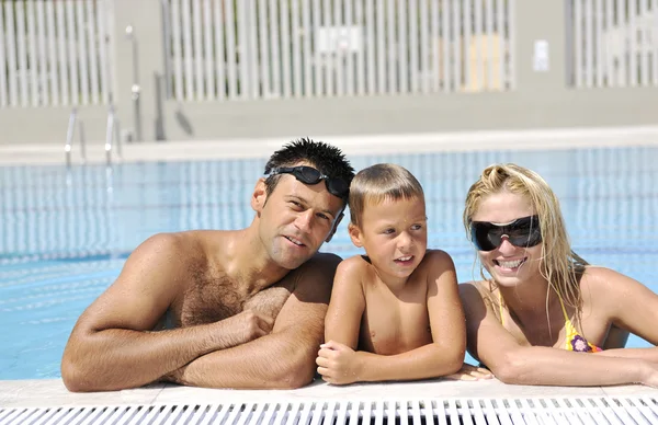 Счастливая молодая семья веселится в бассейне — стоковое фото