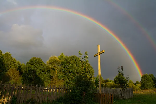 Kruis en regenboog na regen — Stockfoto