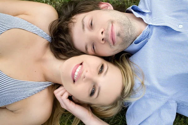 Jovem casal feliz deitado na grama — Fotografia de Stock