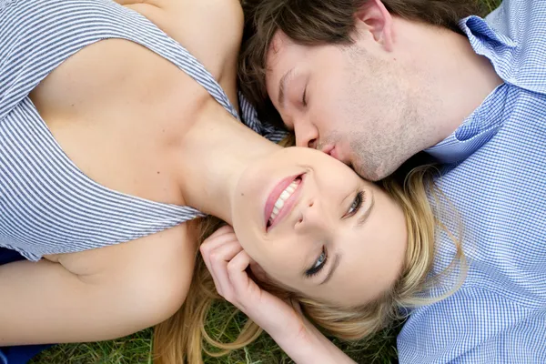 Jovem casal feliz deitado na grama — Fotografia de Stock