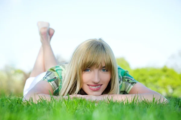Mujer sonriente tendida en la hierba — Foto de Stock