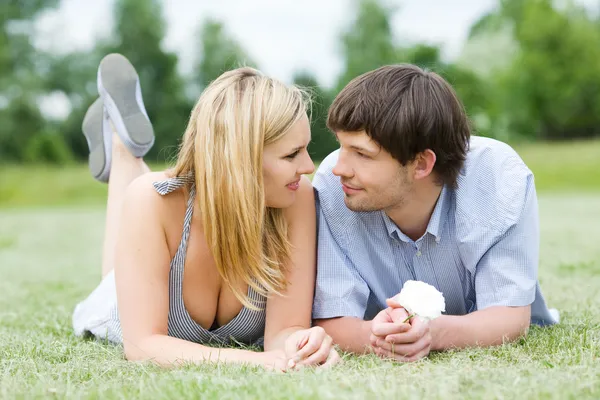 Молода щаслива пара лежить на траві Стокова Картинка