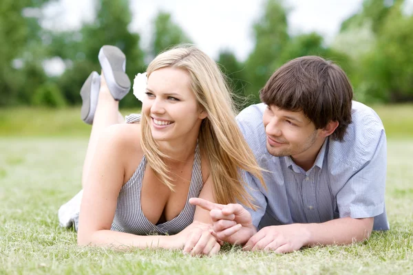 Young happy couple laying on grass — Stock Photo, Image