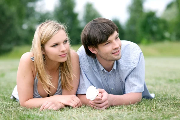 Joven feliz pareja acostada en la hierba — Foto de Stock