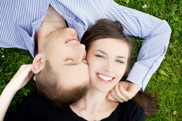 Smiling young couple is cuddle on a gree Stock Picture