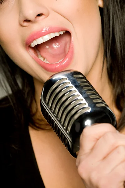 Νεαρή γυναίκα τραγουδά στο μικρόφωνο — Φωτογραφία Αρχείου