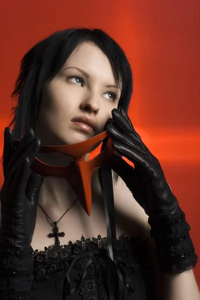 Das gotische Mädchen mit schwarzen Haaren auf rotem Hintergrund — Stockfoto