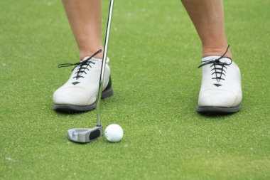 Woman practising golf on chipping green clipart