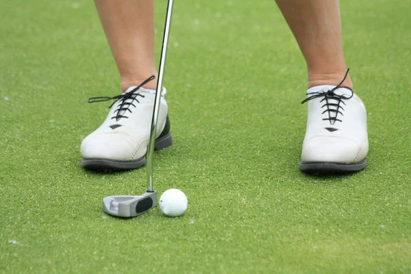 Женщина, играющая в гольф на чип-грине — стоковое фото