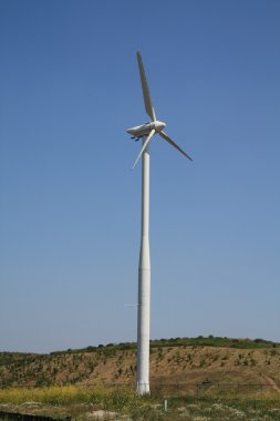 Wind turbine in a clear blue sky clipart