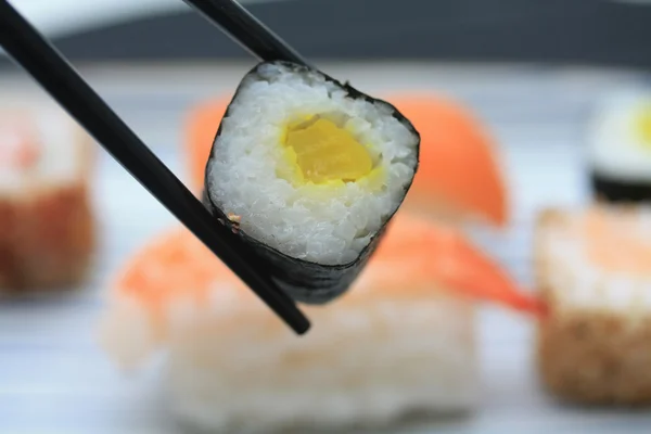 Sushi zwischen Essstäbchen — Stockfoto