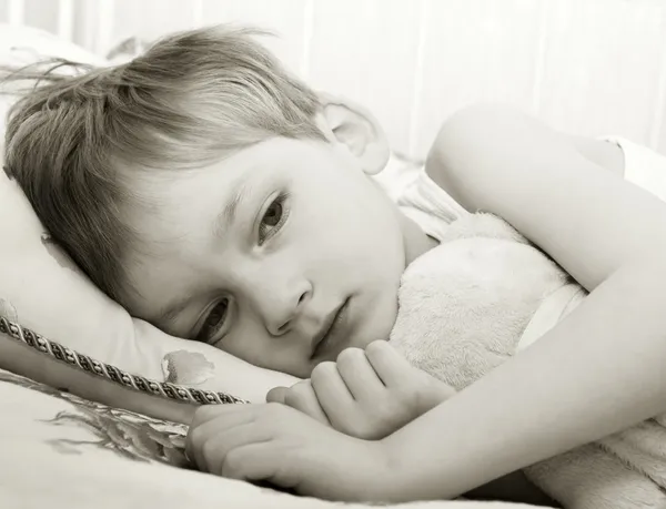 Грустный ребенок в постели — стоковое фото