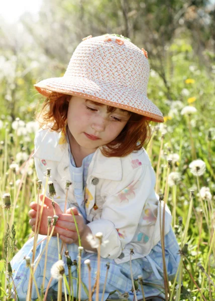 Kleines Mädchen im Feld mit Löwenzahn — Stockfoto