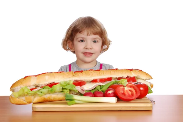 Holčička s velkým sendvič na stole — Stock fotografie