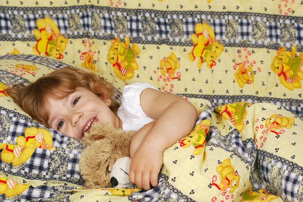 Little girl lying in bed with teddy-bear — Stock Photo, Image