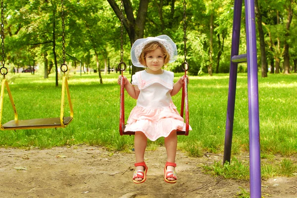 Mała dziewczynka siedzi na huśtawce — Zdjęcie stockowe