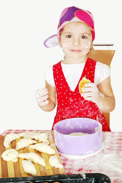 Little girl make and eat croissant — Stock Photo, Image