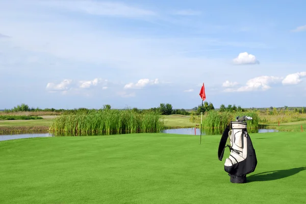 Campo de golfe com bandeira e saco de golfe — Fotografia de Stock