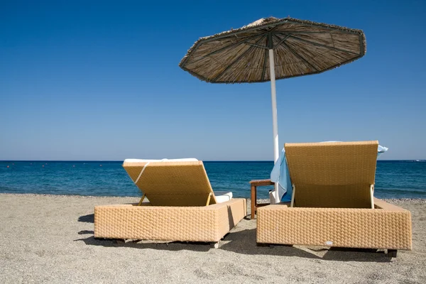 Cadeiras de convés e guarda-chuva na praia — Fotografia de Stock
