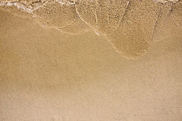 Golf van water op zand strand — Stockfoto