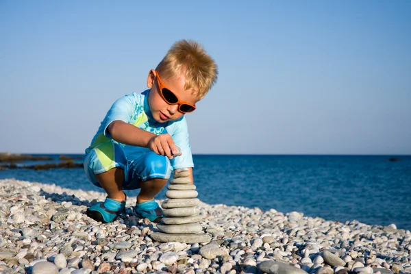 Boy building stone stack — Stock Photo, Image