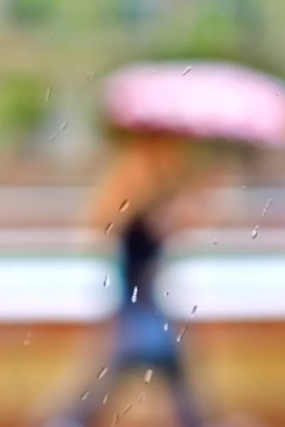 Defocused silhuetten av främmande kvinna med en rosa paraply — Stockfoto