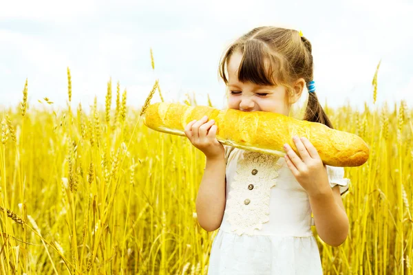 女孩吃一长条面包 — 图库照片