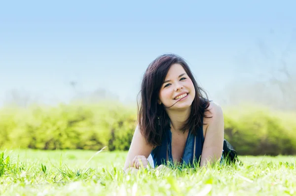 Junges glückliches Mädchen liegt auf Gras — Stockfoto