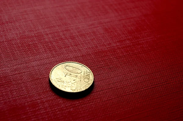 Gold coin on red surface — Stock Photo, Image