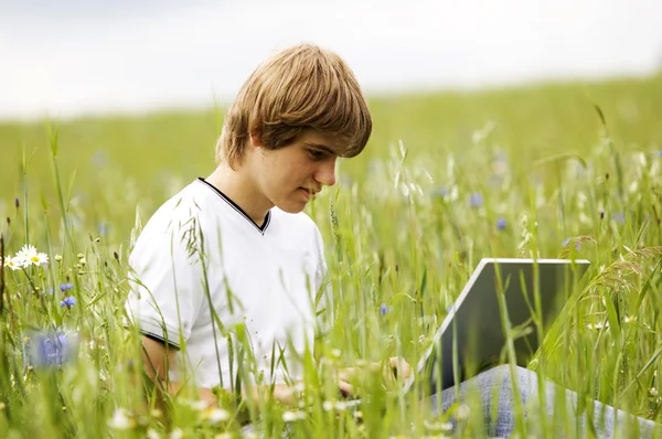 Chłopiec z notebooka na polu — Zdjęcie stockowe