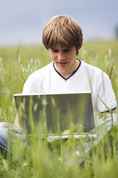 Jongen met laptops op het veld — Stockfoto