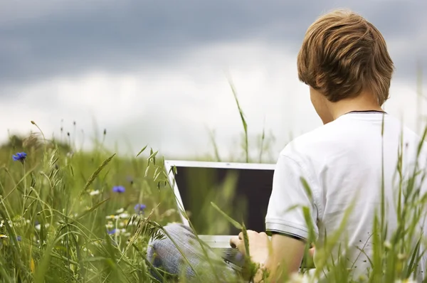 Jongen met laptops op het veld — Stockfoto