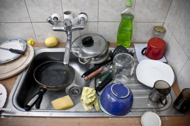 Pile of dirty dishes in the metal sink clipart