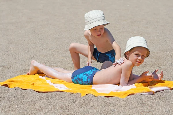 Два Брата Применяют Лосьон Загара Пляже — стоковое фото