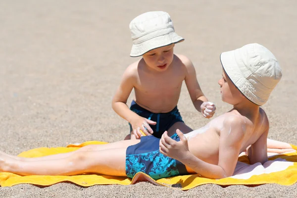 两兄弟在海滩上应用的防晒油 — 图库照片