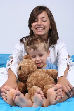 mother and three years old boy in bed - big feet clipart