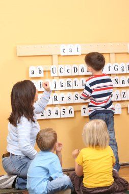 teacher and two preschoolers during lesson clipart