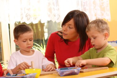 teacher and two preschoolers playing with wooden blocks clipart