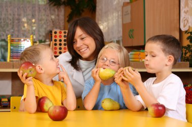 teacher and three preschoolers having break for fruits clipart
