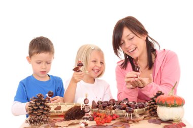 mother with son and daughter making autumn decoration isolated on white clipart