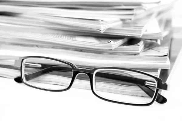 stock image stack of magazines and eyeglasses isolated on white