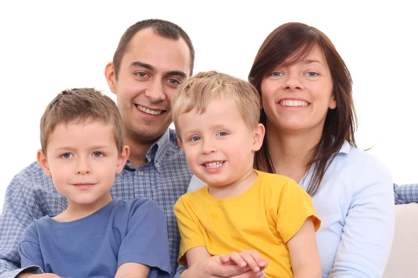 母亲父亲和两个儿子在沙发上 幸福家庭 免版税图库照片