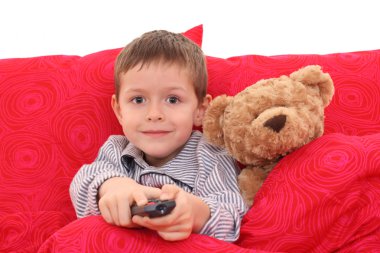 5-6 years old boy watching TV in bed clipart
